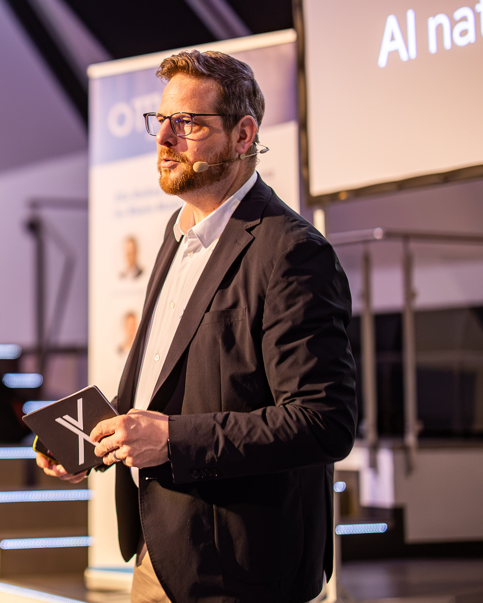 Kai Spriestersbach mit Headset und Moderationskarten bei seiner OMT-Keynote 2026.